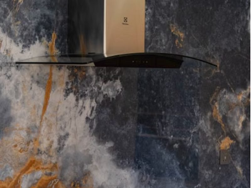 Detalhe de coifa de parede em inox instalada sobre o fogão
