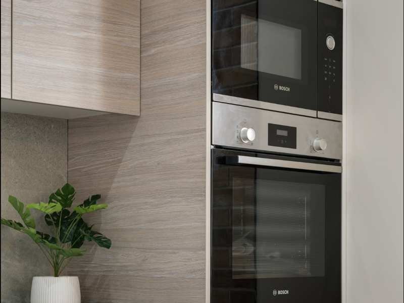 Forno elétrico de embutir preto instalado em coluna de marcenaria com micro-ondas acima