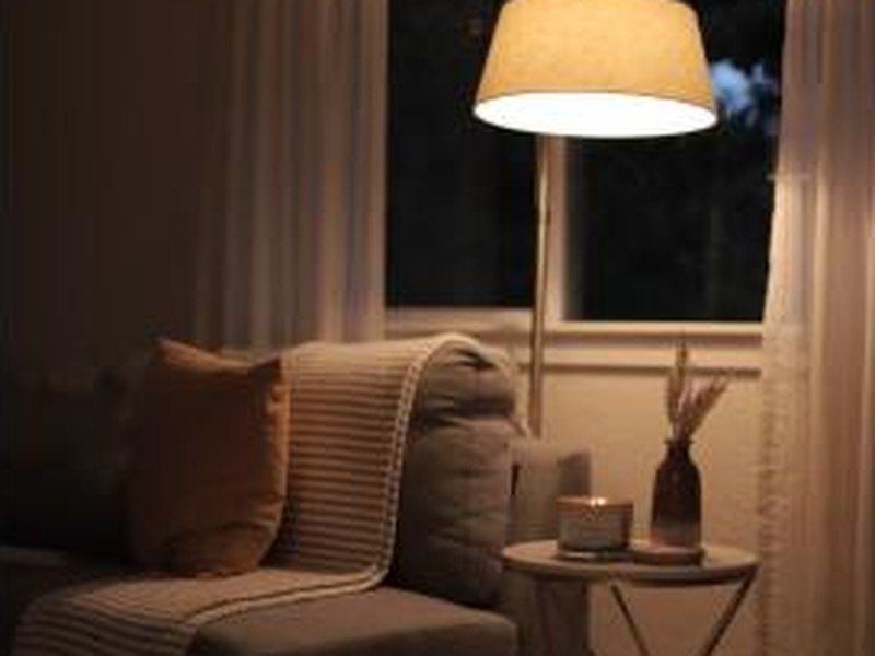 Sala à noite iluminada por luminária de chão com luz amarelada e aconchegante